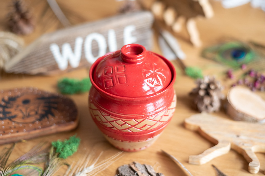Czerwony, ceramiczny pojemnik na smaczki z symbolami słowiańskimi.